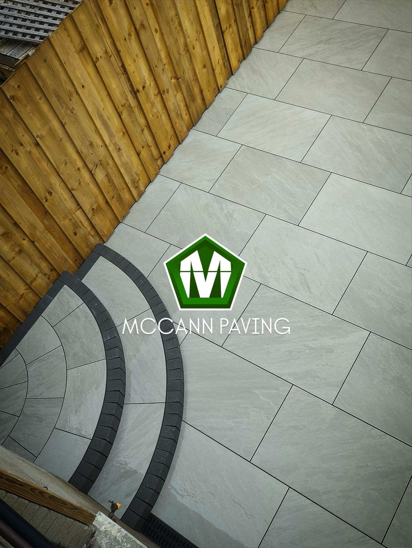 Completed patio with curved step feature and timber fencing by McCann Paving